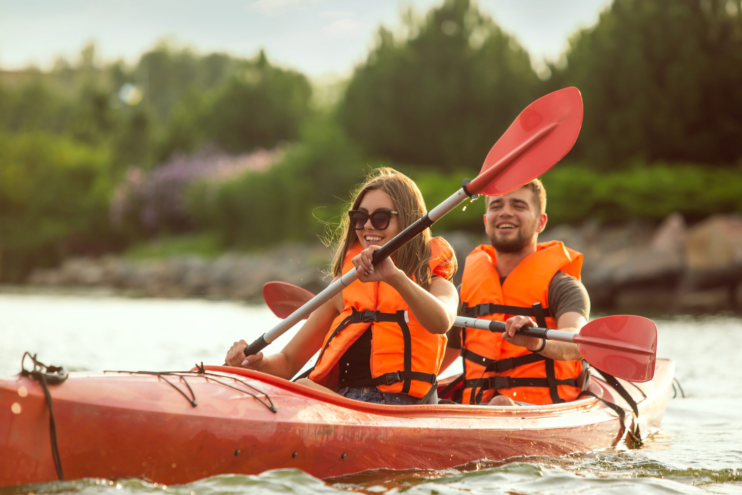 pareja feliz navegando en kayak en el río con la puesta de sol en el fondo